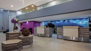 A modern reception area with tiered seating and a mountain mural. - CHN Hotel Monterrey Centro, Trademark by Wyndham (Monterrey)