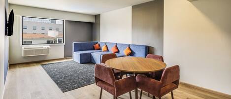A modern living room with a sofa, a round wooden table, and matching chairs.