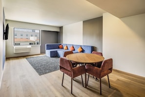 A modern living room with a sofa, a round wooden table, and matching chairs.