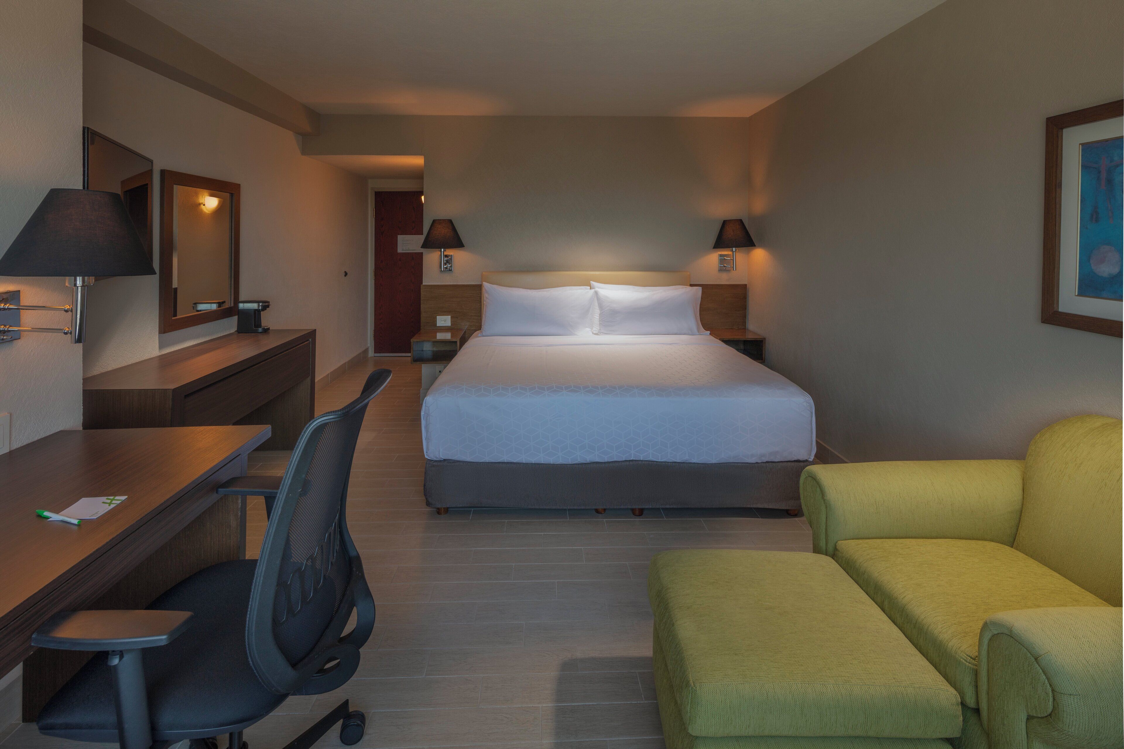 Una camera d'albergo con un letto, una scrivania, una sedia e un divano.