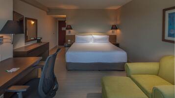 A hotel room with a bed, a desk, a chair, and a couch.