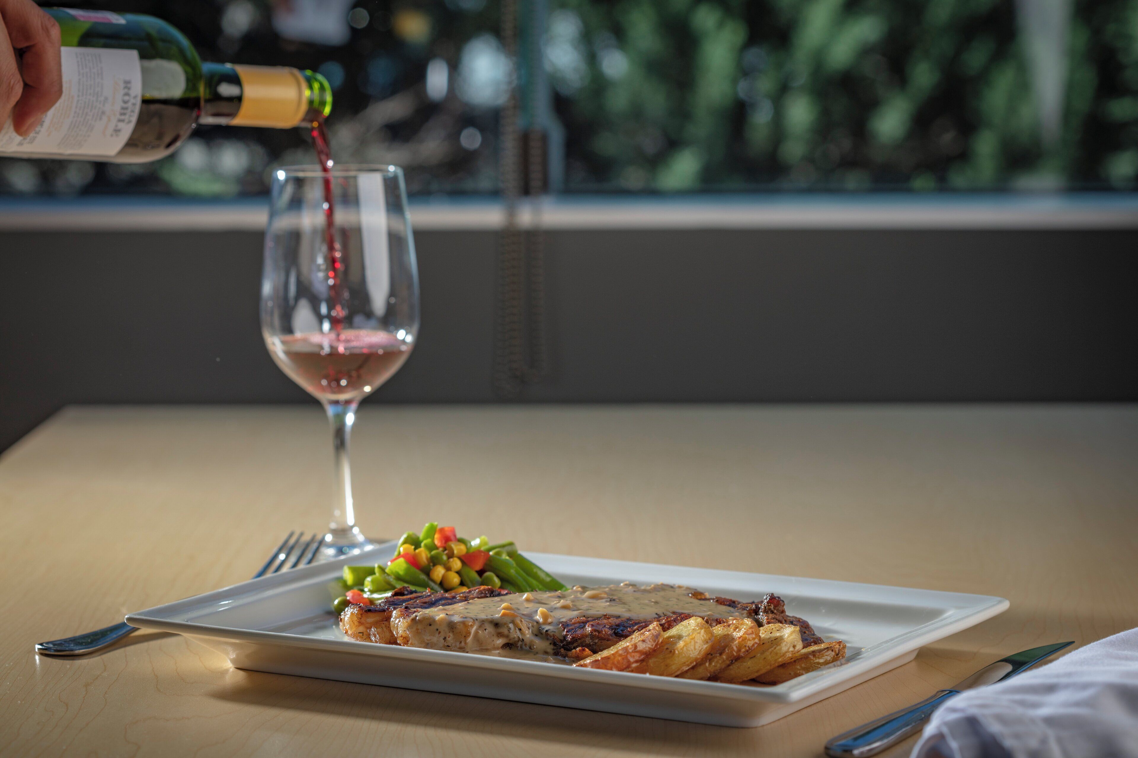 Une assiette de nourriture et un verre de vin rouge en cours de service.