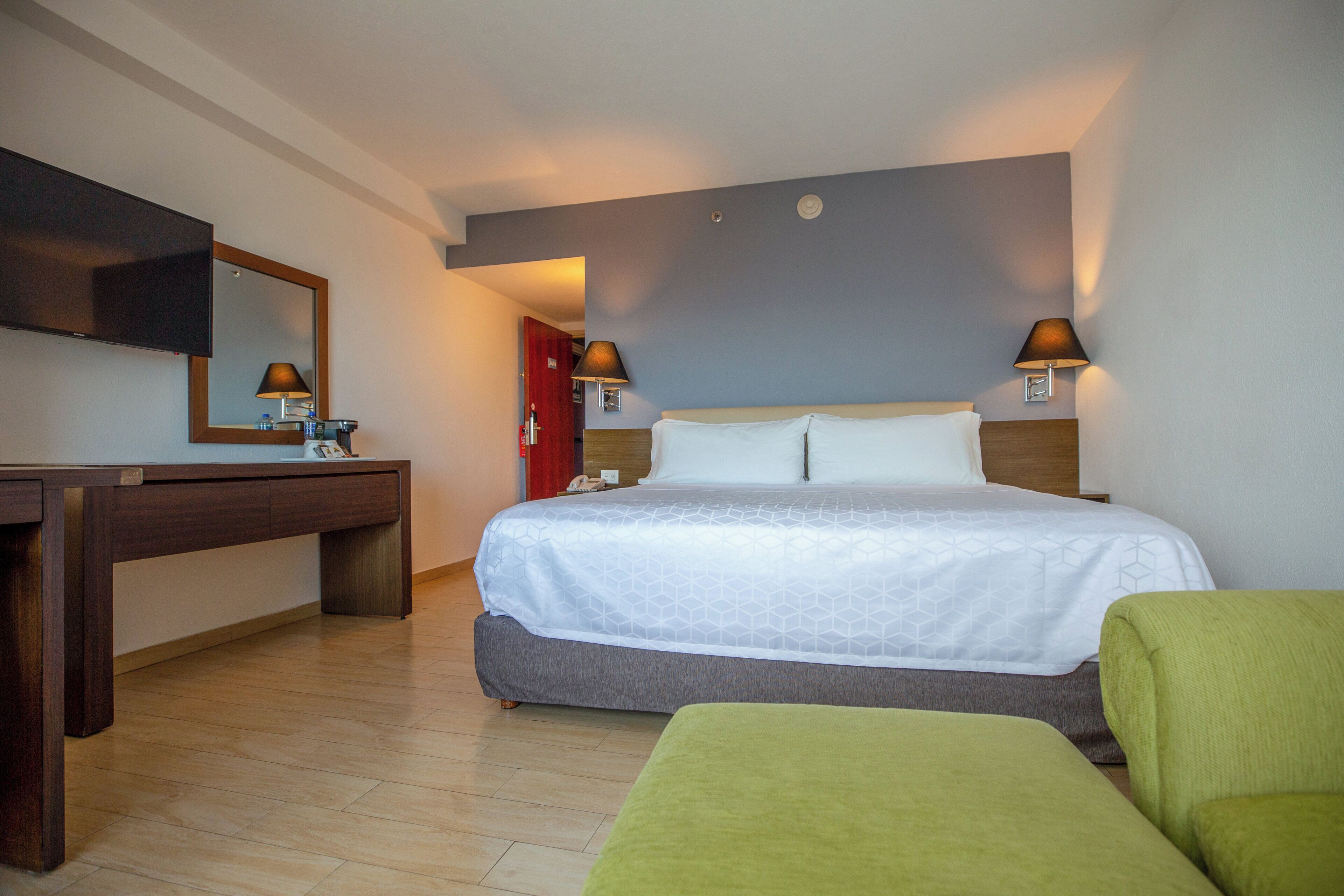 Una habitación de hotel con cama, mesitas de noche, escritorio, silla y televisor.