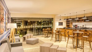 A modern kitchen with bar stools, a dining area with a sofa, and a view of the bar area.