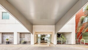 A modern building entrance with a glass door, potted plants, and a concrete floor.