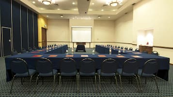 A conference room with a long table, chairs, a projector screen, and a podium.