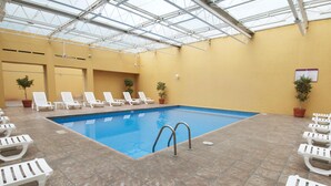 An indoor swimming pool with white lounge chairs and potted plants. - Fiesta Inn Toluca Tollocan (Toluca)