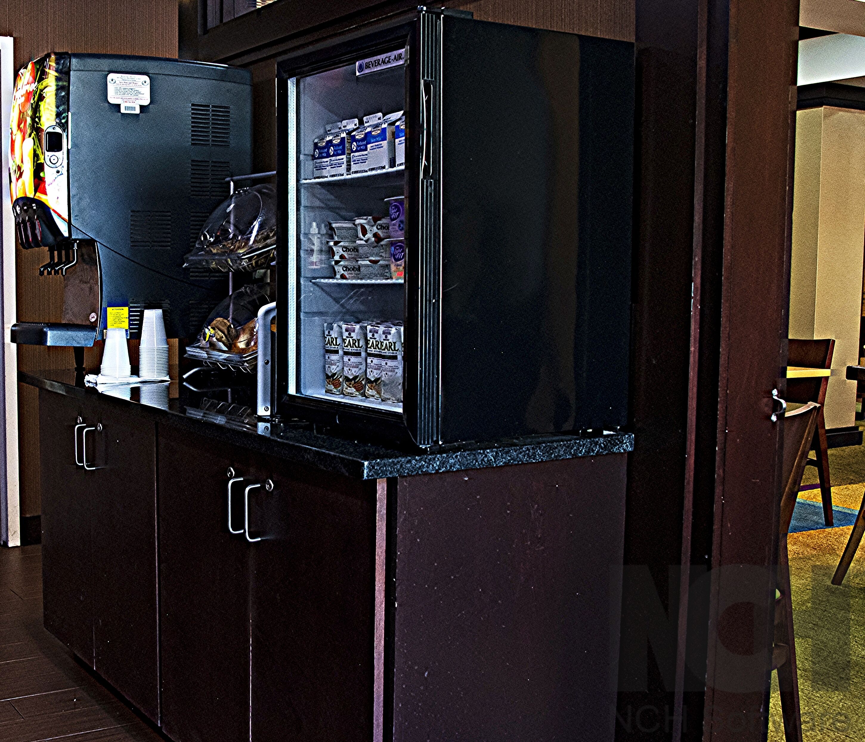 A compact refrigerator with a beverage dispenser, stocked with various drinks and snacks.