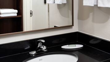 Une salle de bain moderne avec un lavabo noir, un miroir et des serviettes blanches rangées sur un porte-serviettes.