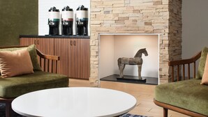 A modern living room with two green armchairs, a white coffee table, and a stone fireplace with a horse sculpture. - Fairfield by Marriott Inn & Suites Jacksonville (Jacksonville)