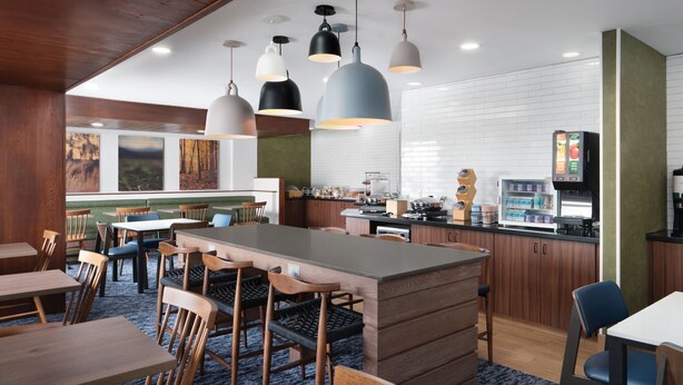 A modern restaurant with a central bar area, wooden furniture, and pendant lighting. - Fairfield by Marriott Inn & Suites Jacksonville (Jacksonville)