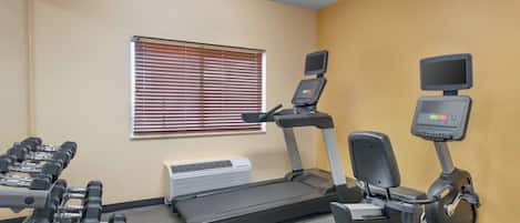 A gym with treadmills, dumbbells, and a stationary bike.