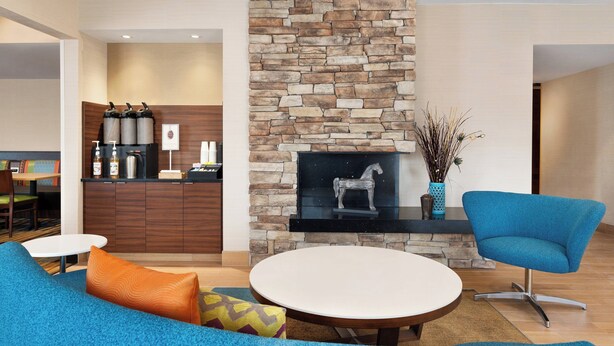 Una sala moderna con chimenea de piedra, una mesa de comedor redonda y un sillón azul.