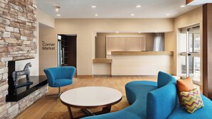 Un interior moderno con un muro de acento de piedra, un sofá azul, una mesa redonda y una zona de cocina.