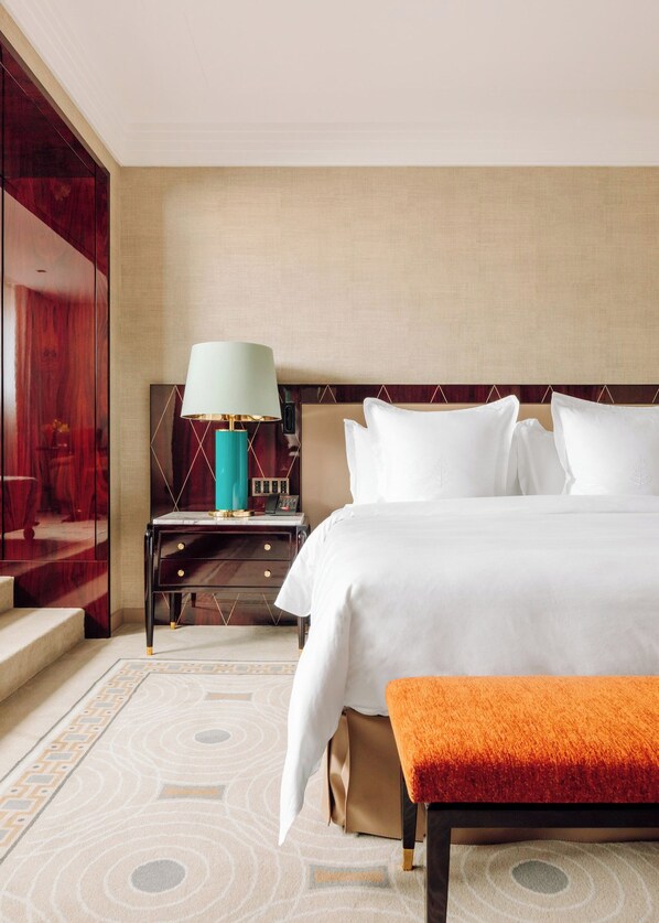 A hotel room with a bed, bedside table, lamp, and a view of a red wall.