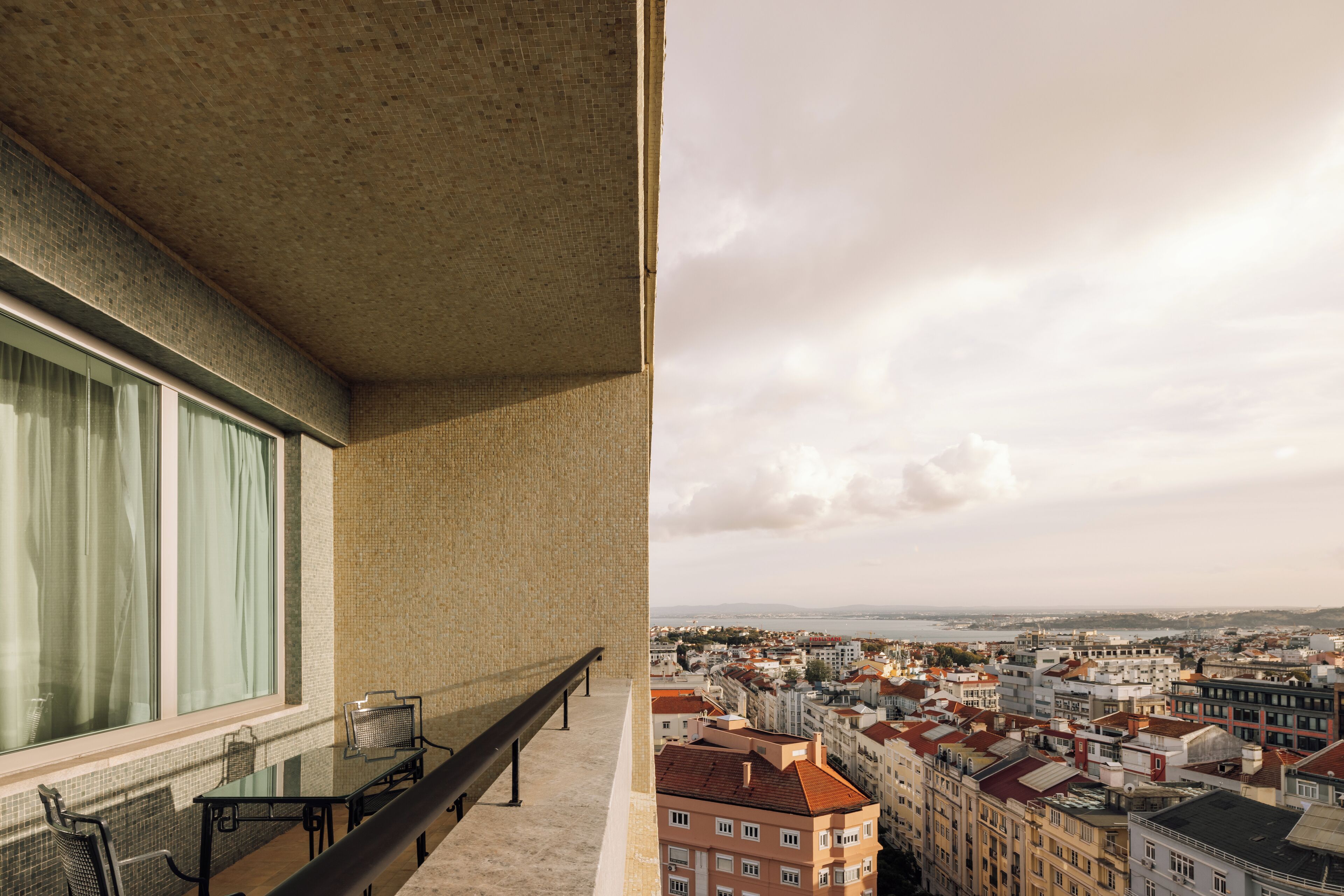 A balcony with a view of a cityscape, including buildings and a body of water.