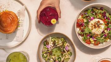 A table with various dishes, including a croissant, a salad, and a dessert.