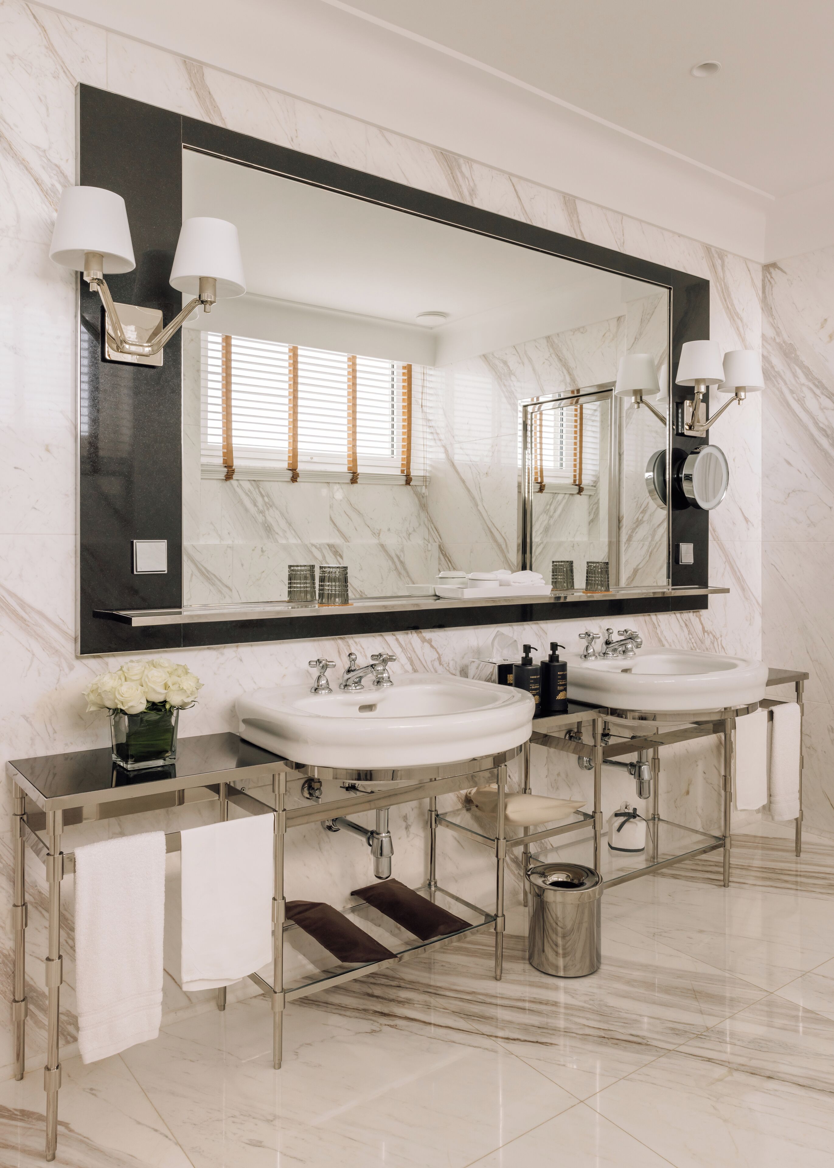 A modern bathroom with two sinks, a large mirror, and a vanity with a towel rack.