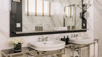 A modern bathroom with two sinks, a large mirror, and a vanity with a towel rack.