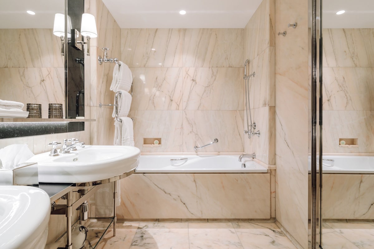 A modern bathroom with two sinks, a bathtub, and a glass-enclosed shower.
