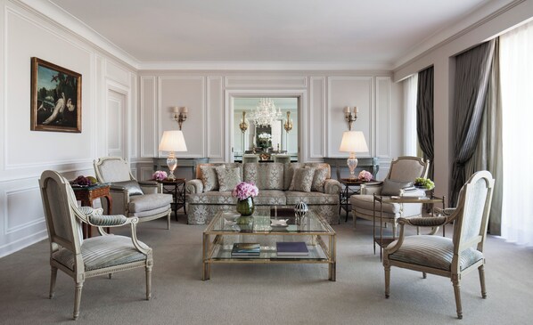 A formal living room with a sofa set, armchairs, a coffee table, and a chandelier.