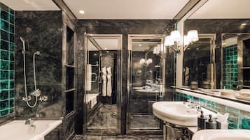 Un baño moderno con bañera, dos lavabos y zona de ducha con mampara de cristal.