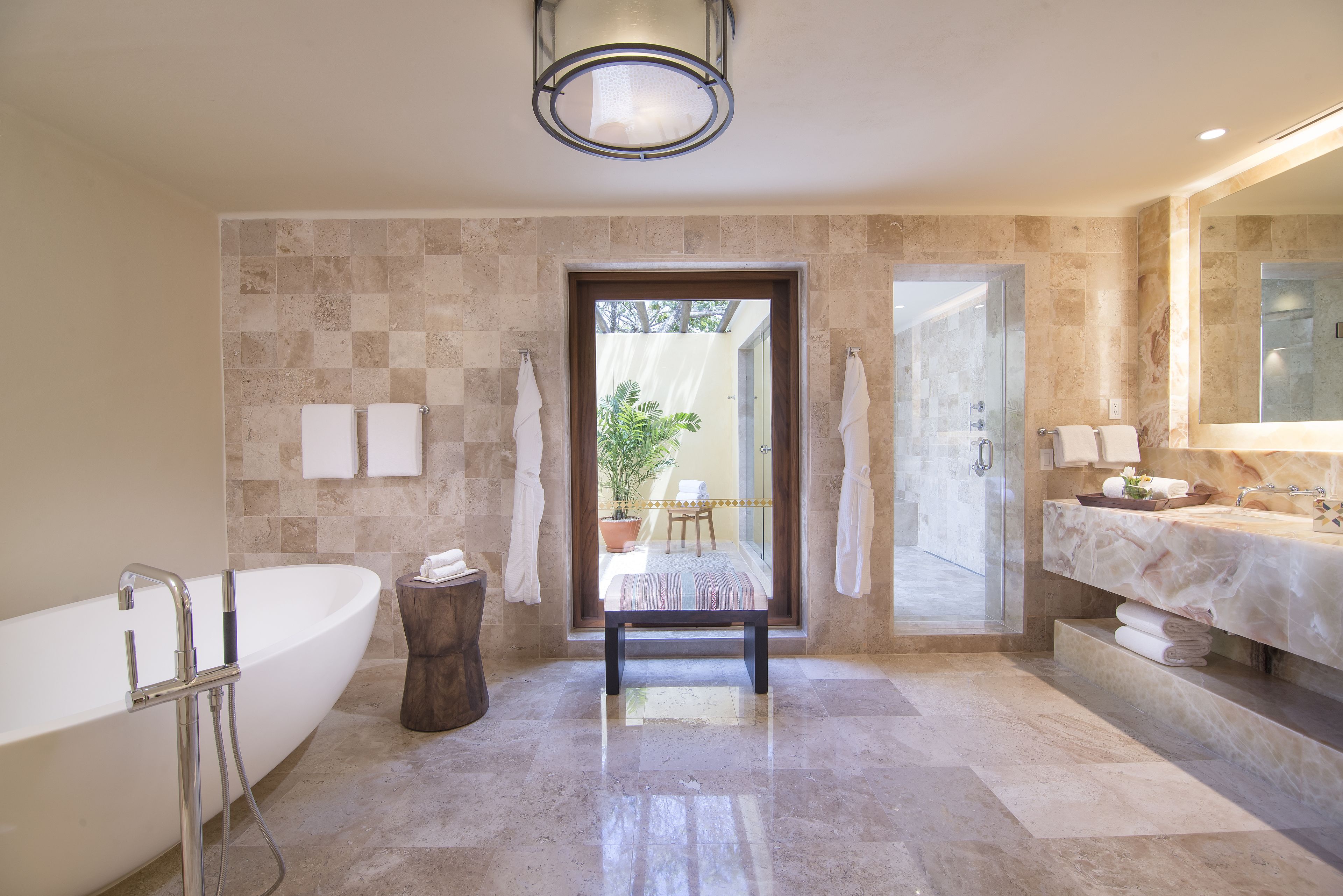A modern bathroom with a freestanding bathtub, a large mirror, and a bench.