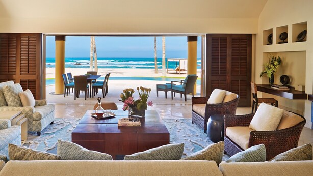 Un vaste salon avec vue sur la plage, aménagé avec des canapés et une table basse.