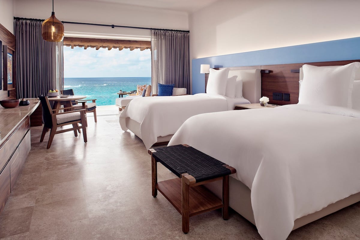 Habitació d'hotel amb dues lliteres, zona de menjador i vista a l'oceà.