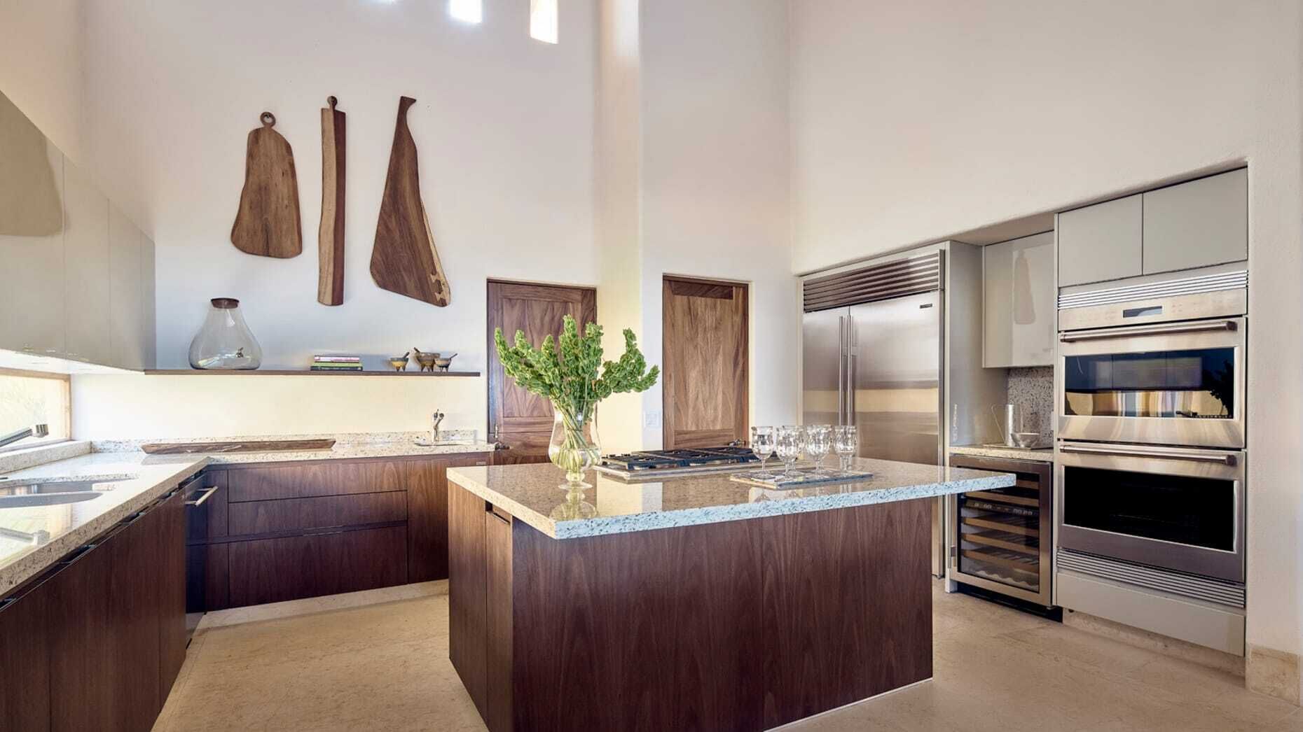 A modern kitchen with a central island, stainless steel appliances, and wooden cabinetry.