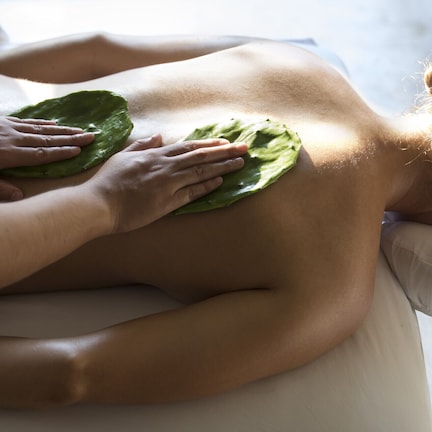 A person receiving a massage with a green leaf on their back.