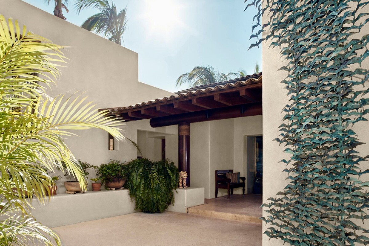 Un patio con una pérgola, plantas en macetas y una zona de estar.