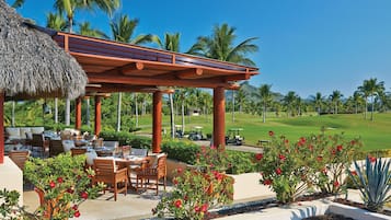 Enjoy al fresco dining under a thatched-roof pavilion surrounded by lush greenery and beautiful flowers.