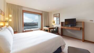 Une chambre d’hôtel avec un grand lit, un bureau, une télévision et une vue sur le paysage urbain.