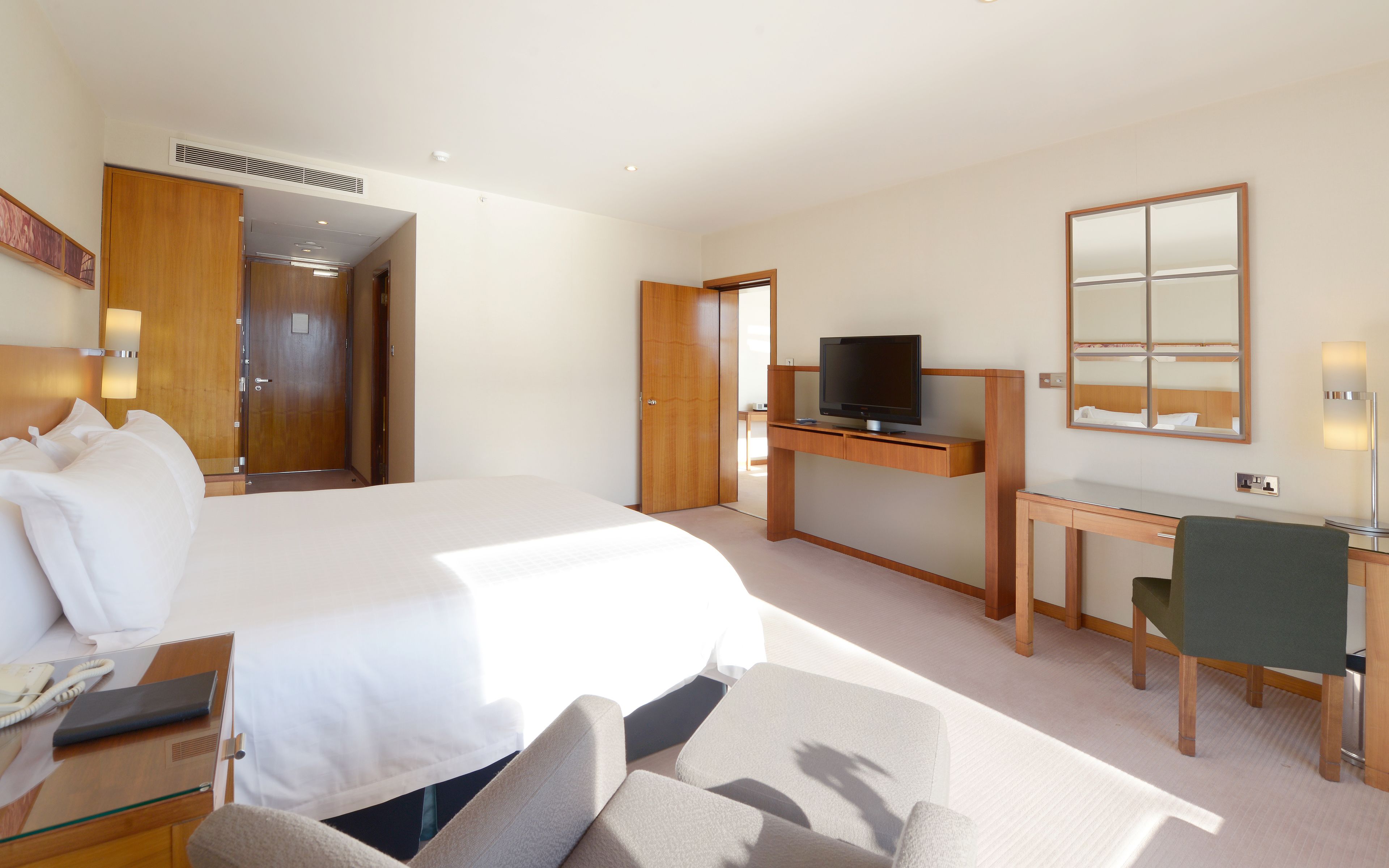 Een hotelkamer met een bed, een bureau met een televisie, een stoel en een spiegel.