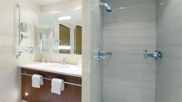 A modern bathroom with a glass shower enclosure, a vanity with a sink, and a mirror.