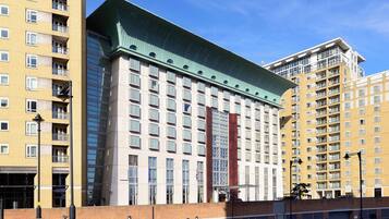 A multi-story building with a modern architectural design, featuring a prominent green roof and a series of balconies.