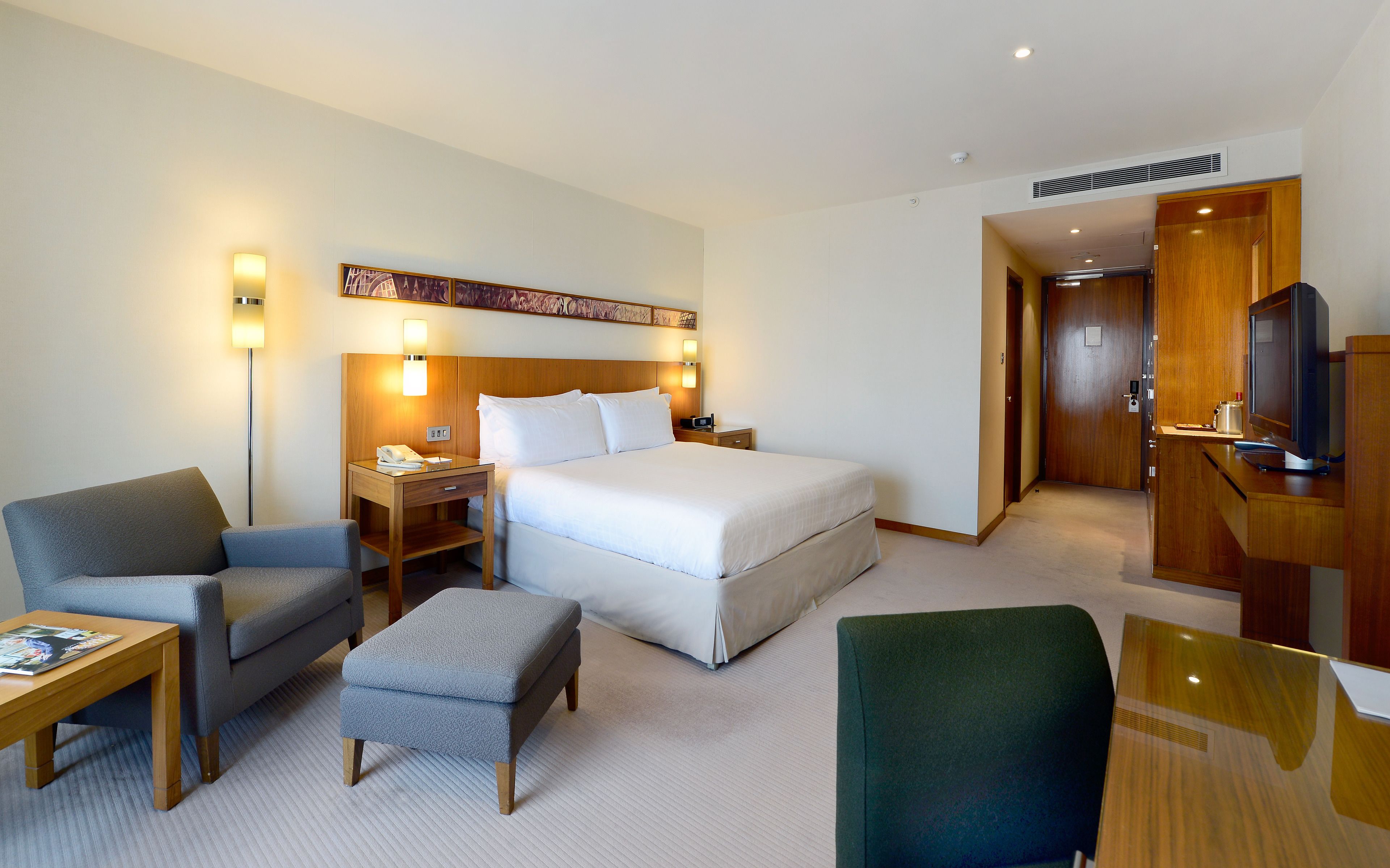 Een hotelkamer met een bed, bureau, stoel, televisie en een kledingkast.