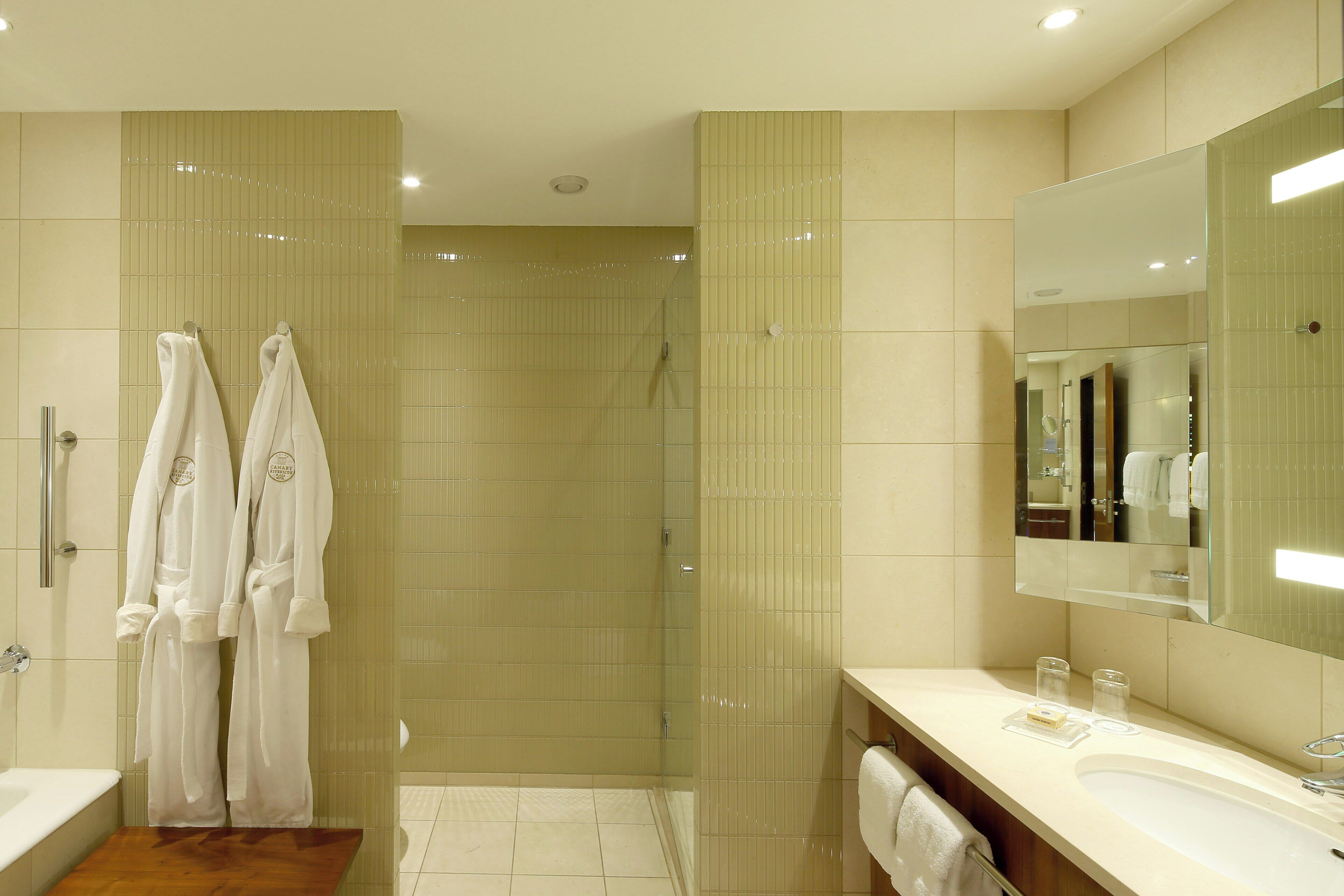Une salle de bain moderne avec une douche à parois de verre, un meuble-lavabo avec un miroir et deux serviettes suspendues sur un porte-serviettes.