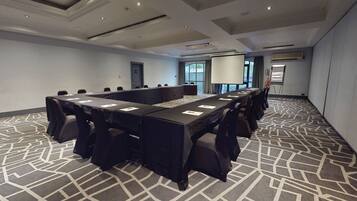 A conference room with a long table, chairs, a projector screen, and a whiteboard.