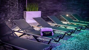 A row of sun loungers with a towel labeled "VILLAGE GYM" and a planter with green plants. - Village Hotel Nottingham (Nottingham)