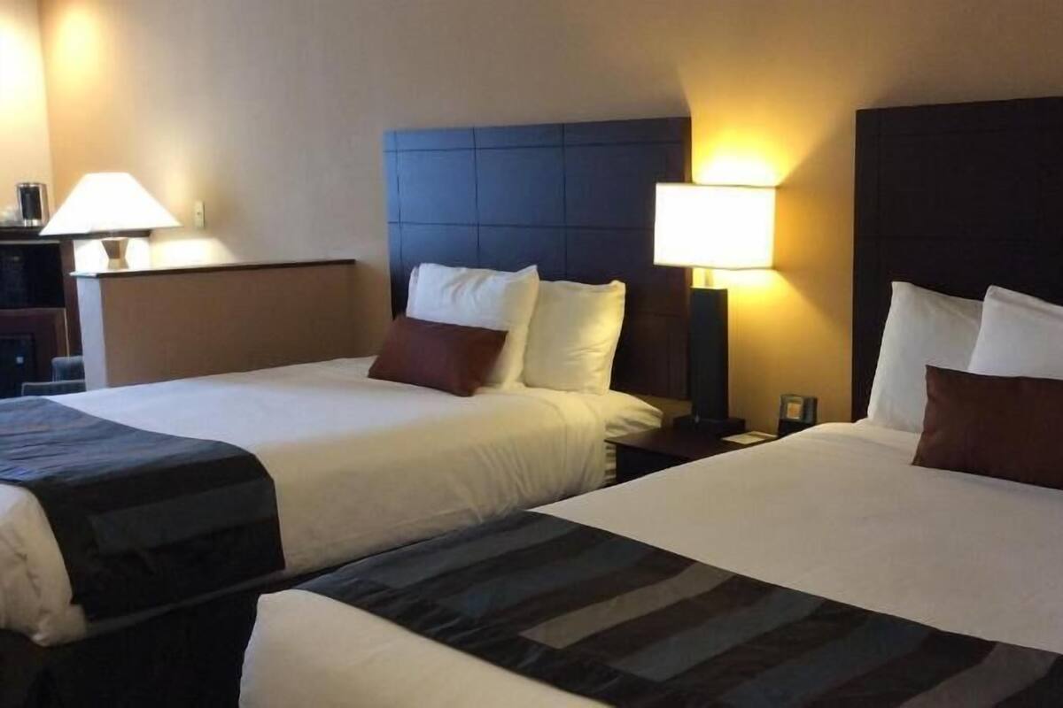 Une chambre d’hôtel avec deux lits, chacun doté d’une tête de lit, de lampes de chevet et d’une table de chevet.