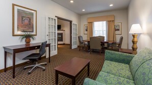 A hotel room with a desk, chair, sofa, dining table, and chairs. - Wingate by Wyndham High Point/Greensboro/Airport South (High Point)