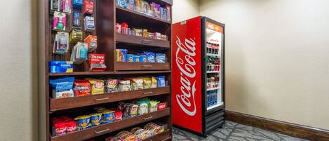 A vending machine stocked with snacks and a Coca-Cola refrigerator.