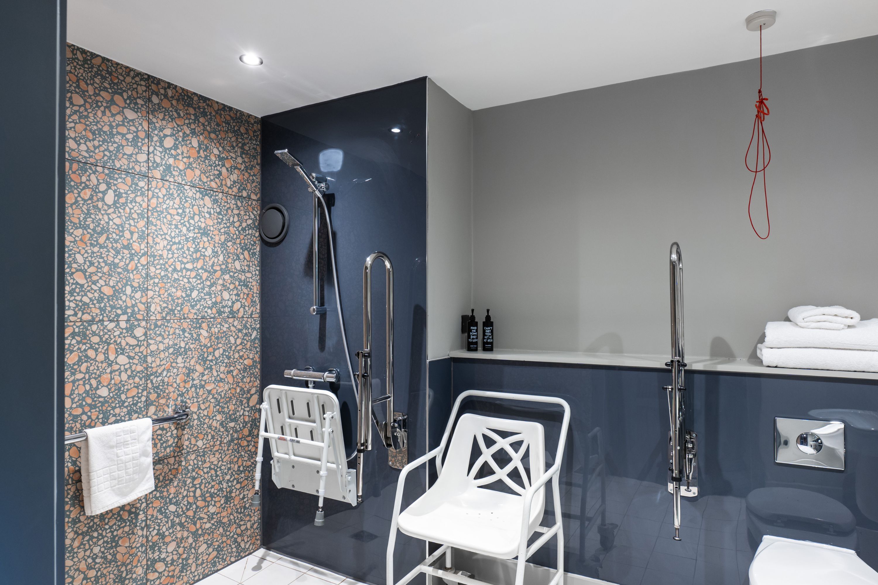 Un baño moderno con ducha, inodoro y una silla blanca.