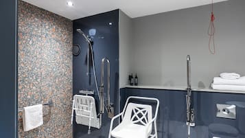 Un baño moderno con ducha, inodoro y una silla blanca.