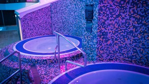A modern bathroom with a mosaic tile wall, a central sink, and a bathtub. - Village Hotel Wirral (Wirral)