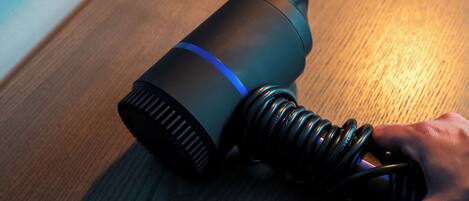 A cylindrical object with a blue stripe, a coiled cable, and a hand holding it.