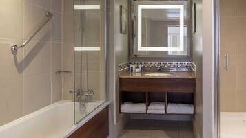 A bathroom with a glass-enclosed shower, a bathtub, a vanity with a mirror, and a towel rack.
