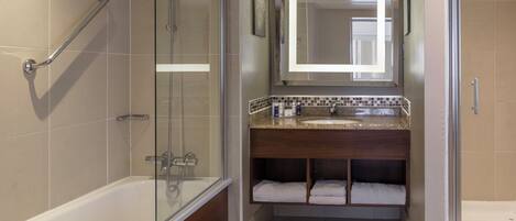 A bathroom with a glass-enclosed shower, a bathtub, a vanity with a mirror, and a towel rack.